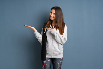 Young sport woman holding copyspace imaginary on the palm to insert an ad