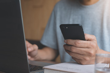 Man working on laptop computer and smartphone