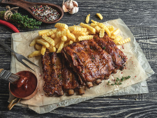 grilled pork ribs with sauce on a cutting board, french fries