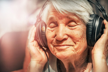 old woman in headphones listening to music