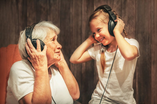 old woman and little girl in headphones listening to music grandmother and granddaughter