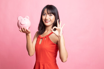 Asian woman show OK  with pig coin bank.