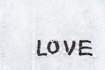 Background of The word love is written in the snow covered wooden area in the winter with copy space.