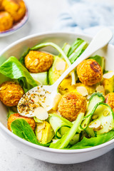 Vegan salad with beans meatballs, avocado and cucumber in white bowl.