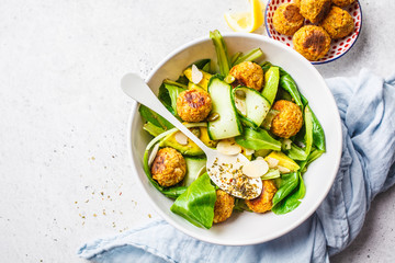 Vegan salad with beans meatballs, avocado and cucumber in white bowl, top view.