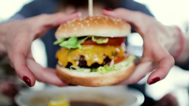 Mum feeds the child a tasty hamburger, cheeseburger
