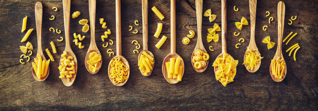 Various Kinds Of Pasta In Wooden Spoons.