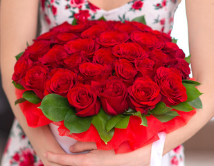 bouquet of red roses in a white box in the hands of a woman