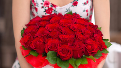 bouquet of red roses in a white box in the hands of a woman