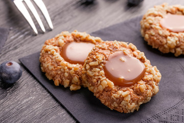 Peanut shortbread cookies with caramel jam inside on a black napkin with blueberries and a patterned dessert fork.