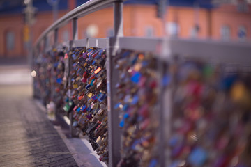 Love locks attached to a bridge in a city, selective focus