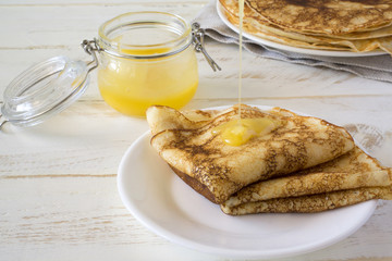 Russian pancakes Bliny with honey on white wooden rustic background. Copy space