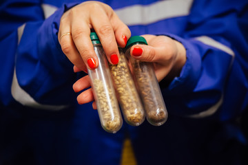 Female brewery worker hands holding malt samples in test tubes