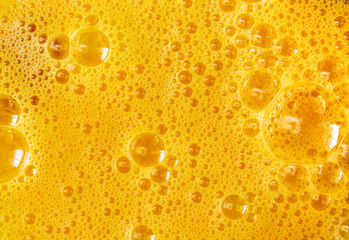 Fototapeta na wymiar Yellow background of beaten chicken eggs with bubbles texture.