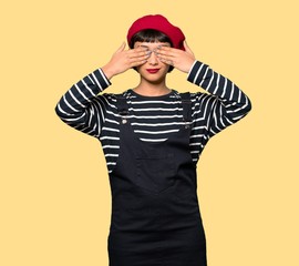 Young woman with beret covering eyes by hands. Do not want to see something over yellow background