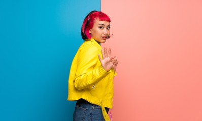 Young woman with yellow jacket making stop gesture with both hands