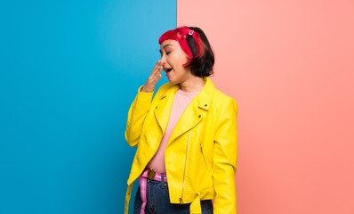 Young woman with yellow jacket yawning and covering wide open mouth with hand