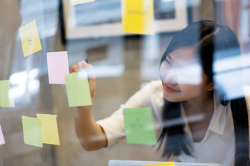 young creative Asian woman use post it notes for reminder