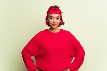 Young woman with red sweater posing with arms at hip and laughing looking to the front