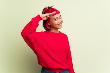 Young woman with red sweater saluting with hand