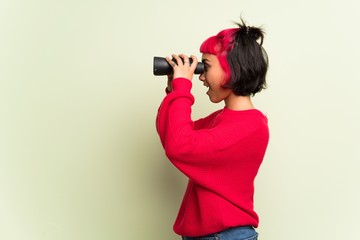 Obraz premium Young woman with red sweater and looking in the distance with binoculars