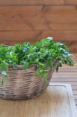 Straw basket full of parsley closeup on the wooden background