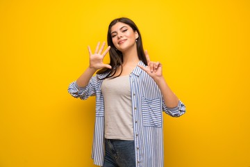 Teenager girl over yellow wall counting seven with fingers