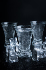 Russian vodka shot with ice on black background