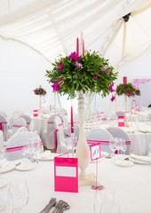 Serving wedding table to celebrate the event with glasses and plates in the restaurant for guests. Decoration with natural flowers and candles