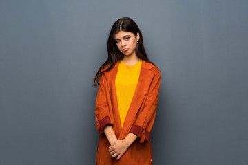 Fototapeta premium Teenager girl with coat over grey wall with sad and depressed expression