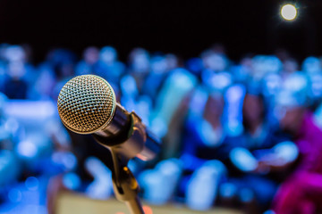 Wireless microphone on the stand. Blurred background. People in the audience. Show on stage in the theater or concert hall.