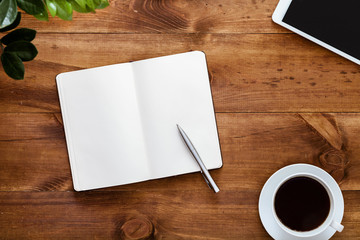 Work space desk with open paper empty white blank page notebook for notes pen and devices on brown wooden table writer workplace creative business goals list background, top view, copy space