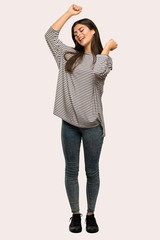 A full-length shot of a Teenager girl with striped shirt celebrating a victory over isolated background