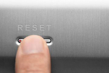 The reset button on the aluminum panel. Male finger. - obrazy, fototapety, plakaty