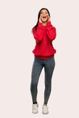 A full-length shot of a Teenager girl with red sweater shouting and announcing something over isolated background