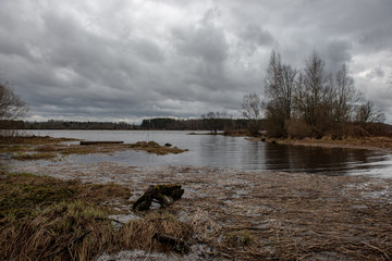 riverside landscape in latvia with dark water and dirty shore line
