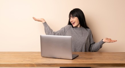 Young woman working with her laptop holding copyspace with two hands