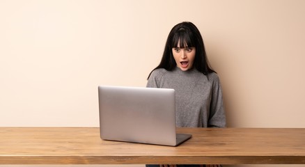 Young woman working with her laptop with surprise facial expression