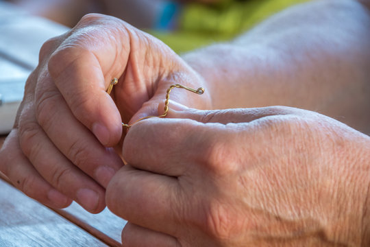 Closeup of old caucasian hands bending a piece of copper wire image with copy space in landscape format