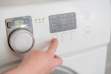 womans hand prepare washing machine and press buttons