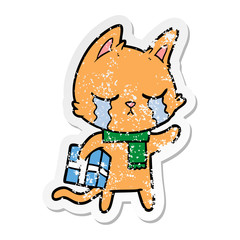 distressed sticker of a crying cartoon cat holding christmas present