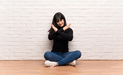 Woman sitting on the floor making NO gesture