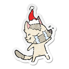 distressed sticker cartoon of a crying wolf wearing santa hat