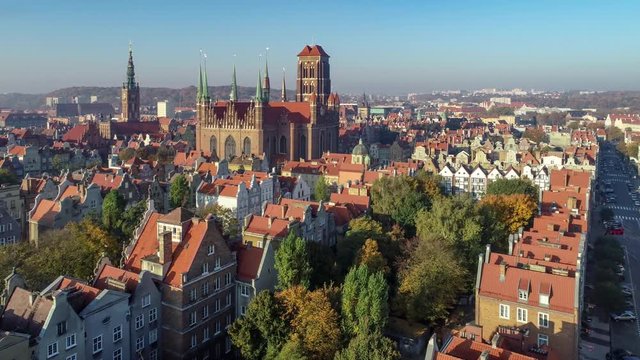 Gdansk, Poland. Old city with Gothic St. Mary church, city hall with clock tower and old historic houses. Aerial approaching video in sunrise ligh