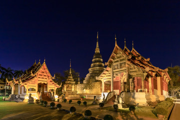 Chapel and golden pagoda at Wat Phra Singh Woramahawihan in Chiang Mai at twilight or night with stars in sky