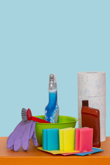 Spring cleaning background. Close-up of house cleaning products and cleaning supplies on wooden table over light blue background. Household chore concept. Macro.