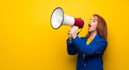 Young redhead woman with trench coat shouting through a megaphone