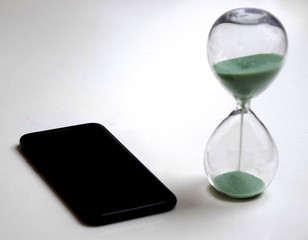 Concept of limiting time spent on smartphone with photo of smartphone and hourglass