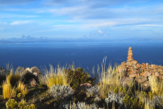 Yellow grass, stones and beautiful background of the blue water, clouds and sky. Photo taken in Peru