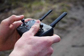 Remote controller in male hands close-up. Man holding transmitter and piloting some vehicle. Drone,...